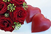 RED ROSES ARRANGEMENT AND TWO HEARTS ON WHITE TABLE
