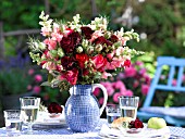 BOUQUET OF ROSES IN A BLUE JUG ON A SET TABLE