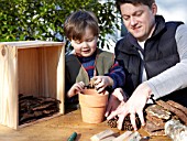 INSECT HOUSE BUILDING PROJECT WITH FATHER AND SON.  PLACING CONES IN POT.  STEP 10