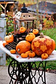 DECORATIVE PUMPKINS WITH LEAF PATTERN ON OLD TABLE WITH LANTERN AND TYPEWRITER