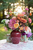 LATE SUMMER BOUQUET OF DAHLIAS, ROSES, ZINNIAS, ASTERS ON OUTDOOR TABLE