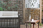 THE DRAWING ROOM GARDEN  URBAN LONDON GARDEN  SEATING AREA AROUND WATER FEATURE THRIUGH CHAIN SCREEN  DESIGNED BY: EARTH DESIGNS.