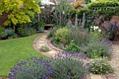 CURVED BRICK AND GRAVEL PATH IN SUBURBAN BACK GARDEN WITH COLOURFUL BORDERS AND LAWN