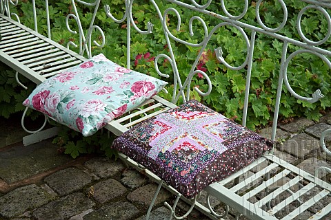 Seating_area_in_garden_lovely_flowered_cushions_on_white_iron_ornate_bench