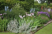 Wide border edged with bricks to lawn, many varieties of herbaceous perennials