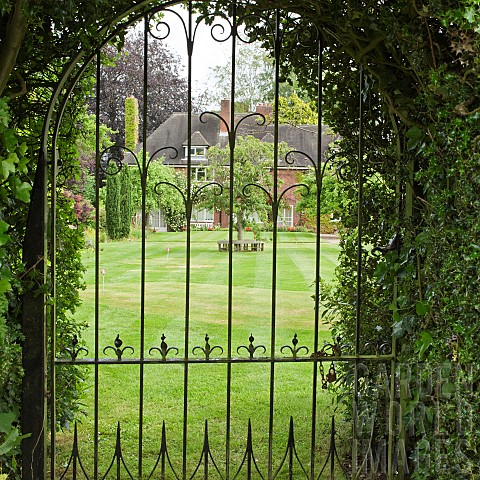 Looking_at_garden_and_house_through_wrought_iron_gate