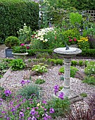 Mixed summer border graveled area with stone sun dial in centre shaped box in square container