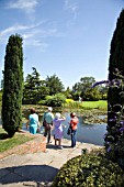 VISITORS WANDER AROUND THE TOP POND AT RHS HYDE HALL GARDENS IN ESSEX.